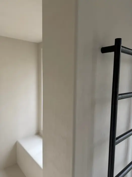 Zwart handdoekrek tegen microcementwand