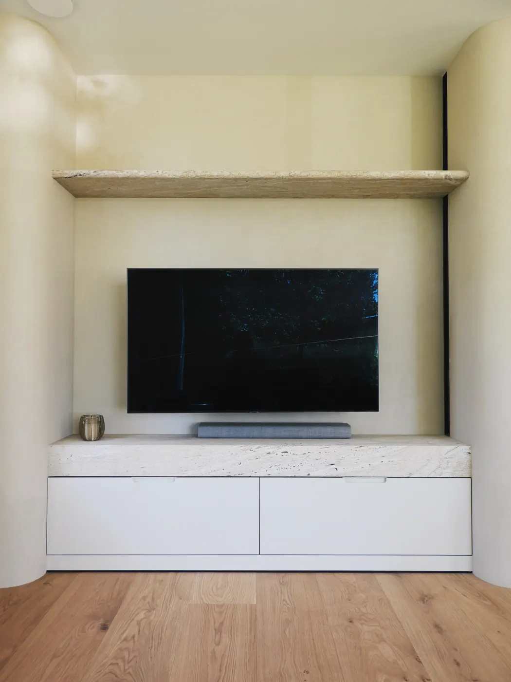 TV-wand in naadloze microcement met travertijn meubel